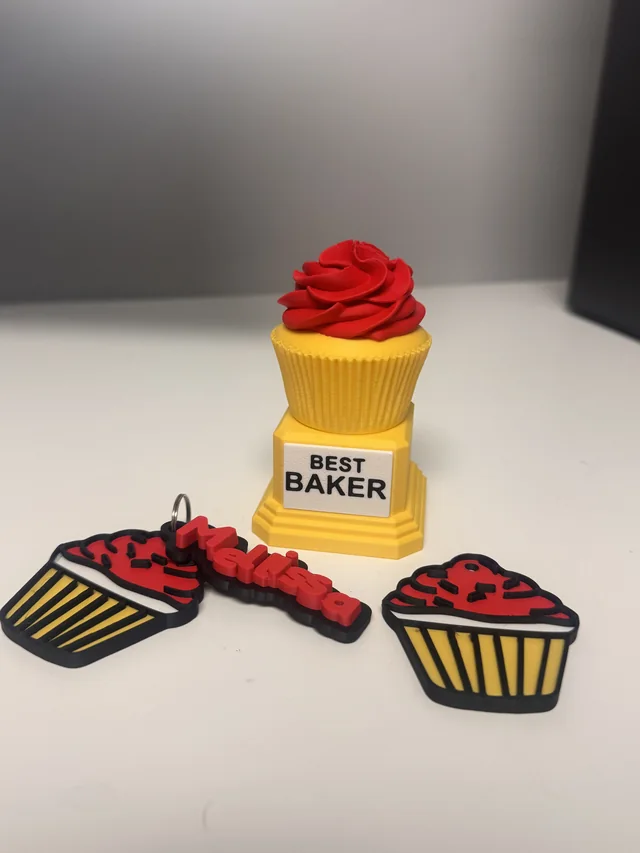 A printed Best Baker cupcake trophy with red icing, two cupcake charms and a personalised name piece