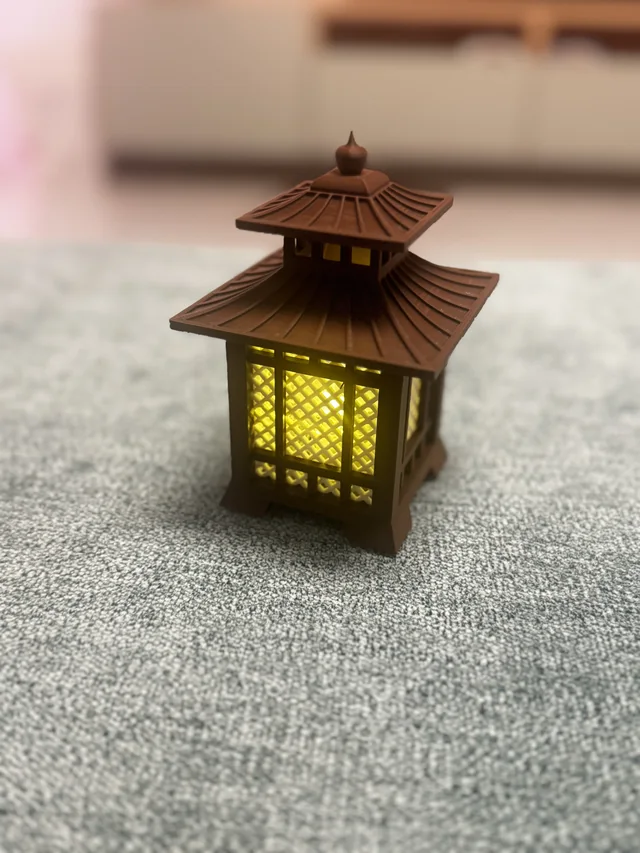 A finished brown pagoda-style lantern with patterned panels and a warm yellow glow
