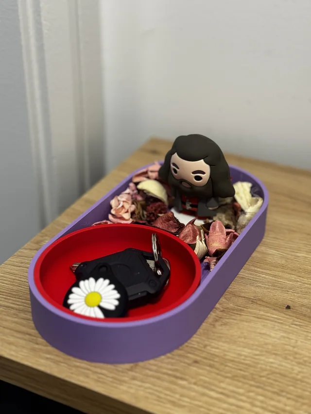 A purple and red printed key stand, styled with a small figure and decorative flowers